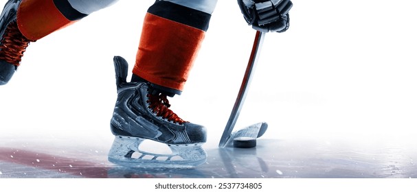 Hockey skates, stick and puck close-up. Hockey player in ice rink. Focus on the puck. Hockey player in action. Ice. Isolated