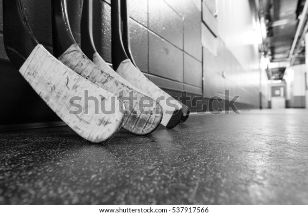 Лезвия хоккейной палочки уложены на грязном полу арены - Неглубокая глубина резкости - Черно-белый