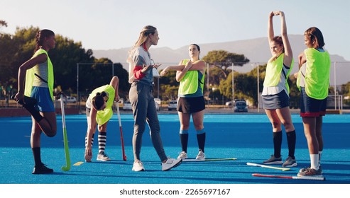 Hockey, women team with coach and sport outdoor, coaching and game strategy, training and fitness on turf. Athlete stretching, start practice and wellness with match plan, motivation and support - Powered by Shutterstock