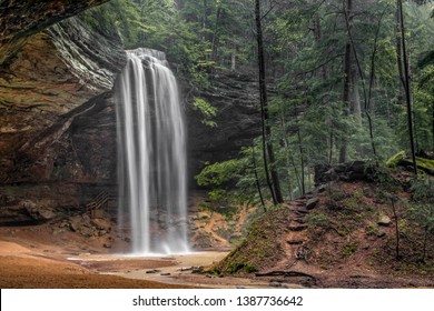 In the Hocking Hills of Ohio, a beautiful, tall, free-falling waterfall graces Ash Cave, an enormous recess cave with an overhanging cliff of Black Hand Sandstone.