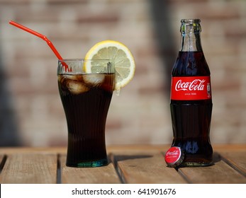 HOEILAART, BELGIUM - MAY 17 2017: A Coca Cola Bottle Next To A Coke Glass, Filled With Ice Cubes And A Slice Of Lemon.