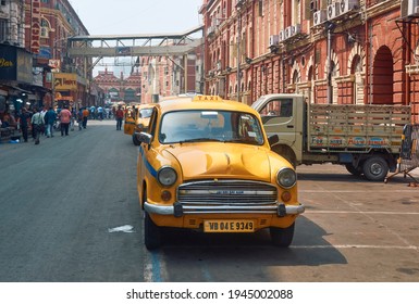 Hog Street, New Market, Kolkata, 03-27-2021: Vintage Looking Yellow Ambassador Taxis Are Parked On Roadside Near Red Brick Walled Heritage Building Of  Kolkata Municipal Corporation.