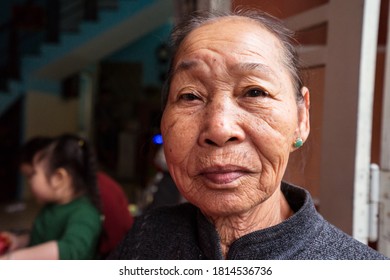 Hoi An / Vietnam - January 18, 2020: Portrait Of Pretty Vietnamese Older Woman In Traditional Dress Sitting At Her Front Door