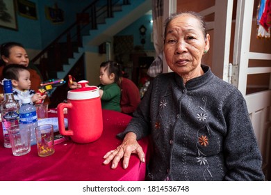 Hoi An / Vietnam - January 18, 2020: Portrait Of Pretty Vietnamese Older Woman In Traditional Dress Sitting At Her Front Door