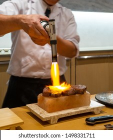 Hokkaido Beef Medallions Being Seared With A Torch On A Salt Block, Omakase Style.