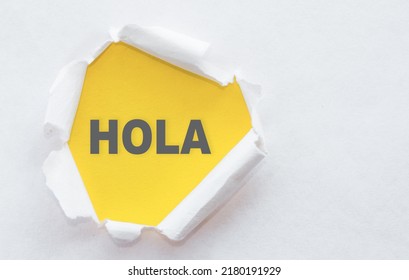 Hola Word In Spanish Language On Yellow Background Under White Torn Paper.