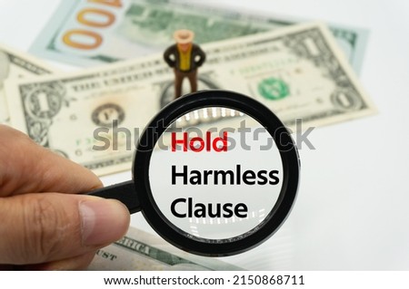 Hold Harmless Clause.Magnifying glass showing the words.Background of banknotes and coins.basic concepts of finance.Business theme.Financial terms.