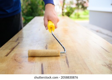 Hold The Lacquer Roller On The Wood Plank. Waterproof Paint On Wood. Lacquer Roller.