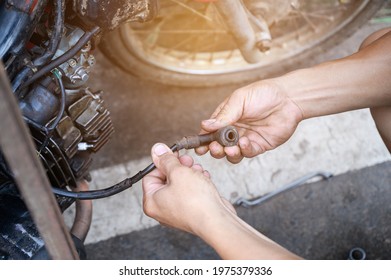 Hold A Spark Plug Resistor Motorcycle. Motorcycle Mechanic Replacing Spark Plugs.