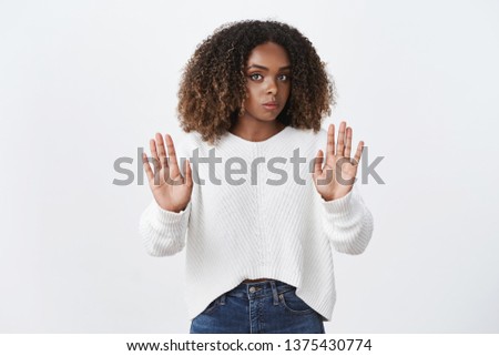 Hold your horses, slow down. Intense displeased and reluctant serious-looking african american female hearing disturbing proposal frowning and showing stop gesture, refusing and showing rejection