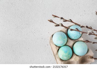 Holder with beautiful Easter eggs and willow branches on light background, closeup