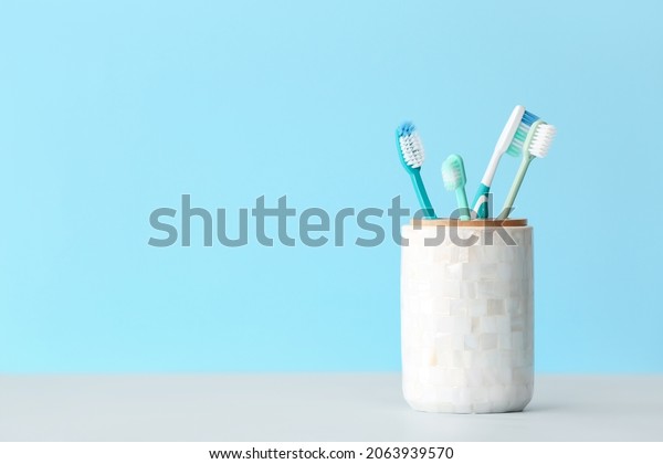 Holder with\
toothbrushes on color\
background