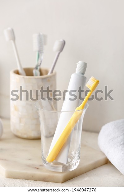 Holder with toothbrushes and toothpaste on table\
in bathroom