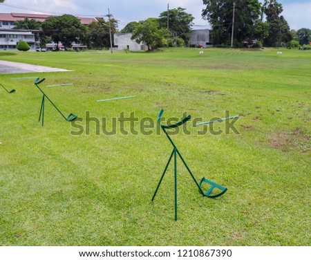 Green​ steel​ golf​ bag​ holder which is placed on the grass in the golf course for​ facilitate the golfers. 