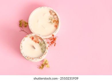 Holders with candles and flowers on pink background - Powered by Shutterstock