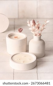 Holders with candles and reed diffuser on white tile background