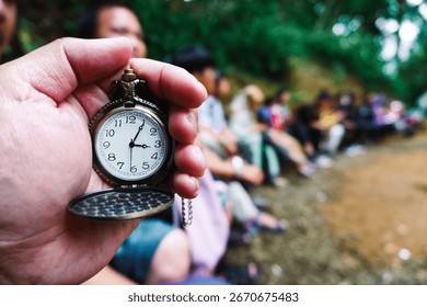 Holding an antique clock with a queue of visitors in the background