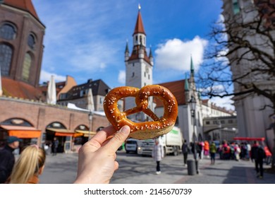 holding bayern style pretzel on the victuals market with altes rathaus background in munich - Shutterstock ID 2145670739