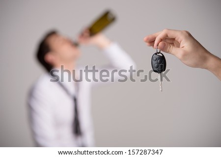 Holding car keys with drinking man on background