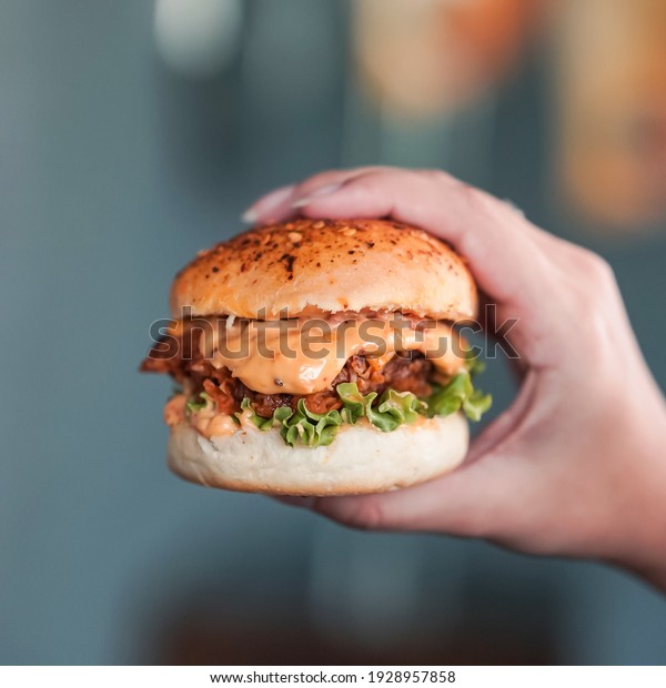 Holding cheesy burger in\
hand