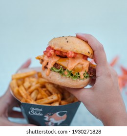 Holding Cheetos Slider Burger In One Hand And Fries Bucket In Other Hand