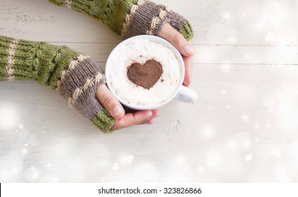 Holding Coffee Latte Cup With Cocoa Shape And Cozy Wool Hands Warmers On Magic Winter Background