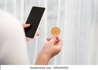 Holding crypto coin and mobile phone on white background