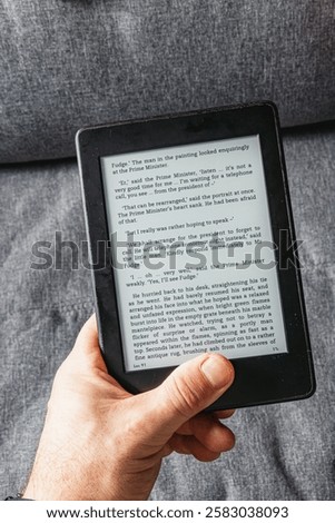Holding an e book in hand while comfortably seated, immersed in a captivating story during a beautiful reading week. The cozy ambiance enhances the reading experience.