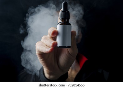 holding e liquid bottle for electronic cigarette, isolated ecig flavor bottle for vape devices over a black background. 