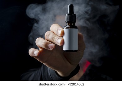 holding e liquid bottle for electronic cigarette, isolated ecig flavor bottle for vape devices over a black background. 