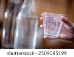 Holding glass of water at a cafe. Premium filtered water at a restaurant. Sparkling or still water, soda, mineral water or hydration options drinking from a glass. Close up view.