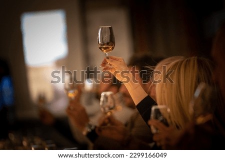 Holding glass of whisky at a tasting event.