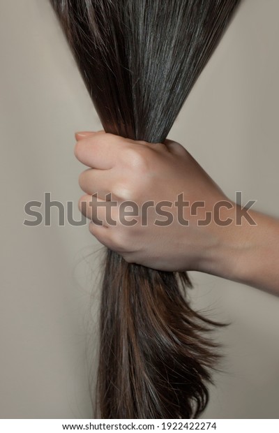 Holding hair in hands.\
Strong dark hair.