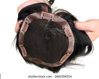 Holding a hair toupee or topper exposing the inside and showing the clips to help secure the hairpiece.