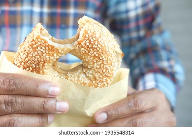 Holding Half Eaten Fresh Bagel Bread In A Paper 