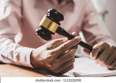 Holding Hammer law. at office with contract papers on wood table. Signing of advisor Concepts and vintage, Sunset light.Selective Focus - Powered by Shutterstock