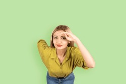 Holding Hand At Forehead,  Young Blonde Girl Leaning Forward Smiling Looking Camera Paying Attention Holding Hand At Forehead. Isolated Over Light Green Background, Copy Space. Lifestyle Concept.