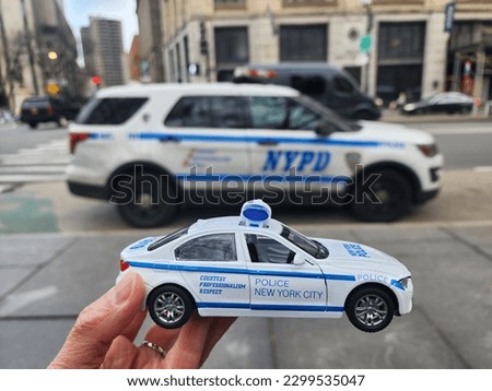Holding hand of Model Police New York City car compare to NYPD car park along the street
