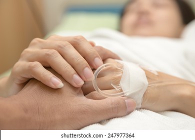 Holding the hand of a sick loved one in hospital bed