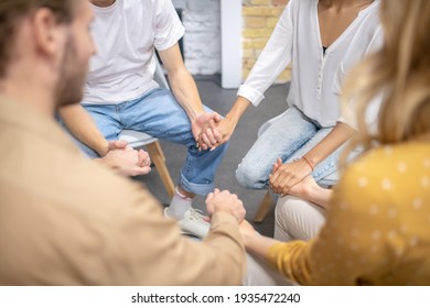 Holding Hands. Close Up Picture Of People Sitting In A Cirlce And Holding Hands