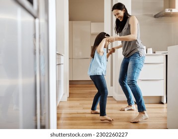 Holding hands, dance and a child with a mother in the kitchen, bonding and quality time together. Smile, laughing and a mom teaching her daughter with dancing, love and happiness with fun in a house - Powered by Shutterstock