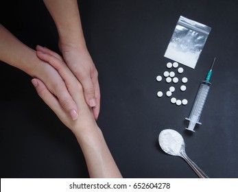 Holding hands for helping drug addict teenage on black table with drug powder, syringe and pills. Stop drug addiction by rehabilitation in rehab center concept. International Day against Drug abuse.