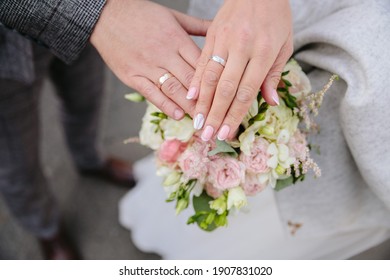 Holding hands with wedding rings. Bridal bouquet is held with bridal hands. Invitation to the wedding ceremony. Wedding rings. Flowers and shoes for the bride. Bridal shoes and  jewellery