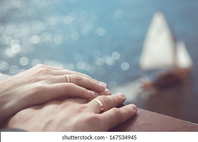 Holding Hands with wedding rings on the background of sea and sun.