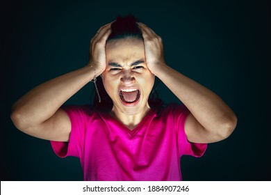 Holding head. Portrait of young crazy scared and shocked caucasian woman isolated on dark background. Copyspace for ad. Bright facial expression, human emotions concept. Looking horror on TV, cinema.