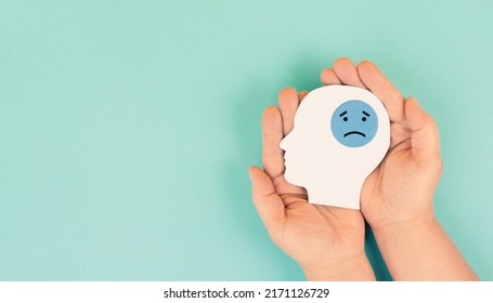 Holding a head with a sad face in the hands, mental health concept, negative mindset, support and evaluation symbol 