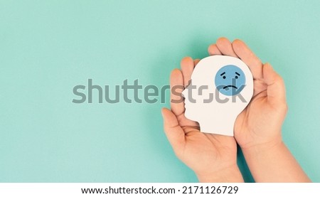 Holding a head with a sad face in the hands, mental health concept, negative mindset, support and evaluation symbol 
