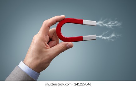 Holding a horseshoe magnet against a gray background with magnetic field attracting