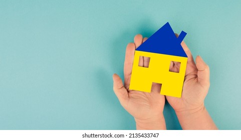 Holding a house in the hand with the colors of the ukrainian flag, home for refugees from Ukraine, help for families - Shutterstock ID 2135433747