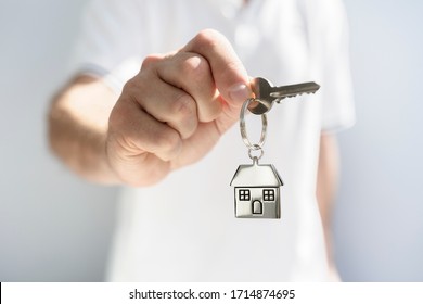 Holding House Keys On House Shaped Keychain Concept For Buying A New Home